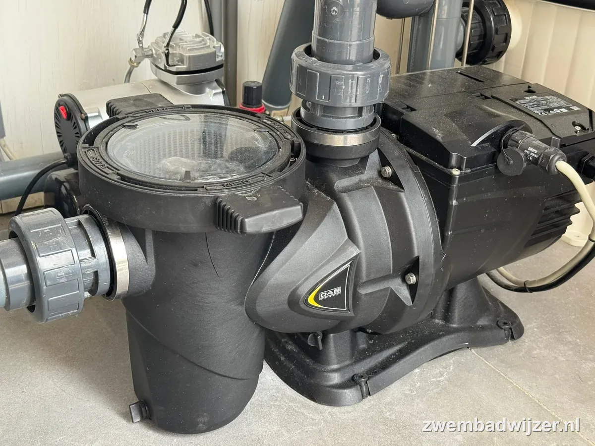 Zwarte DAB zwembadpomp met transparant voorfilter en grijze PVC-leidingen in de technische ruimte