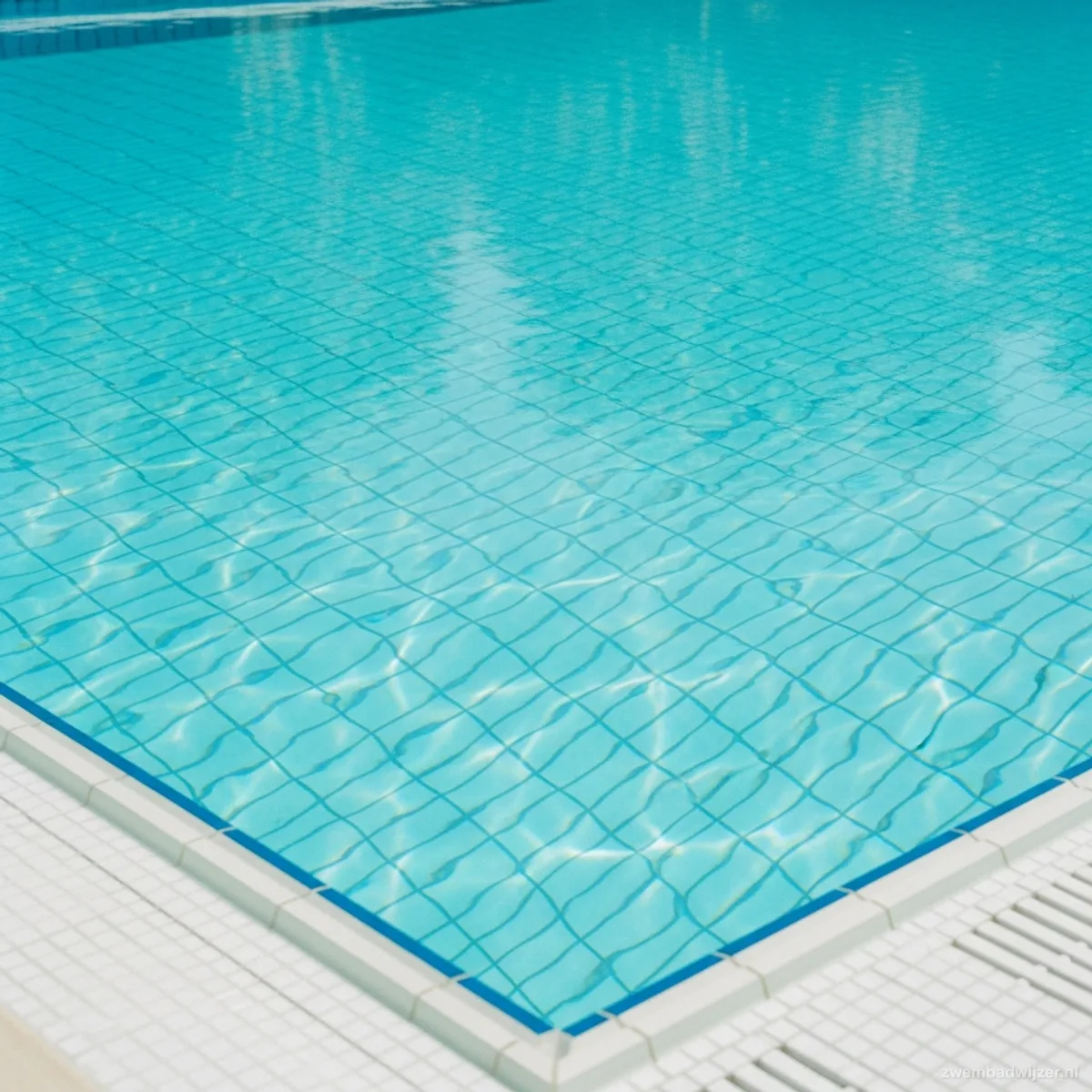 Clear turquoise pool water in spring with light caustic patterns on white mosaic tiles on the floor
