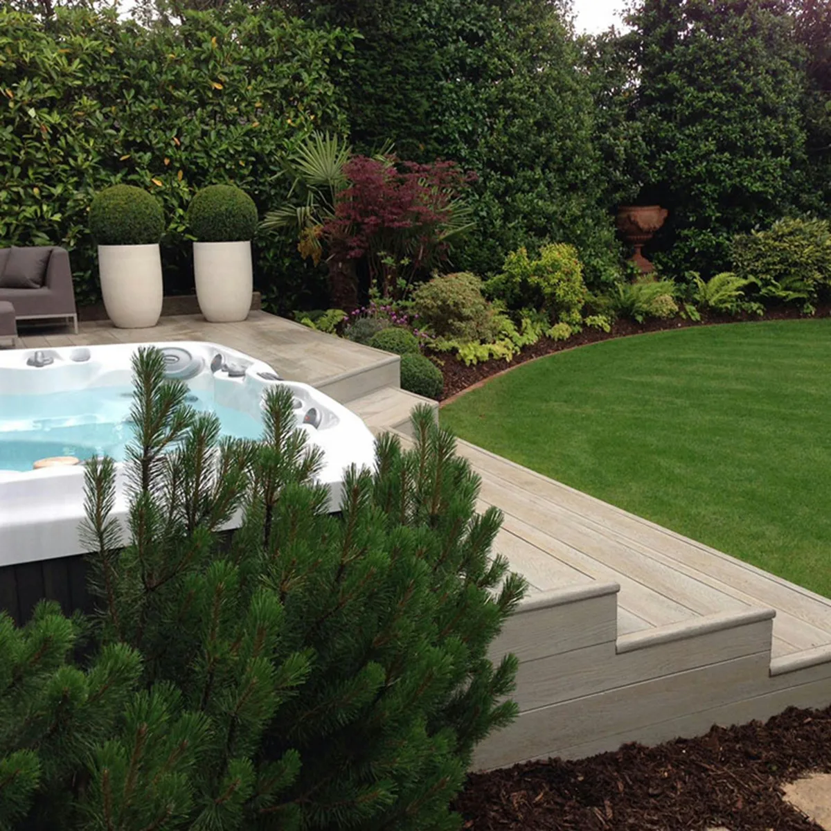 Houten jacuzzi in een tuin met groene beplanting